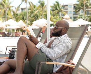 A man on the beach reading a book.