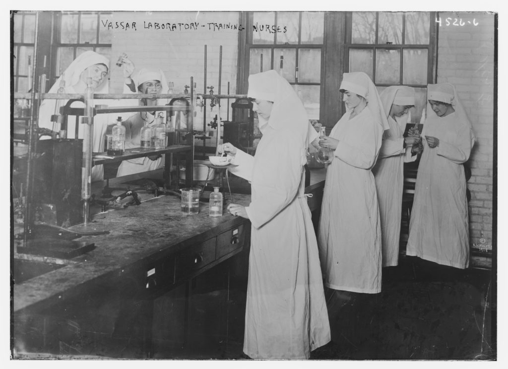 Old photograph of nurses in all-white outfits in a laboratory